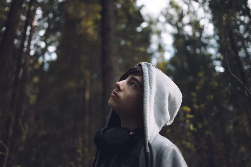 Teenage boy looking up at treetops