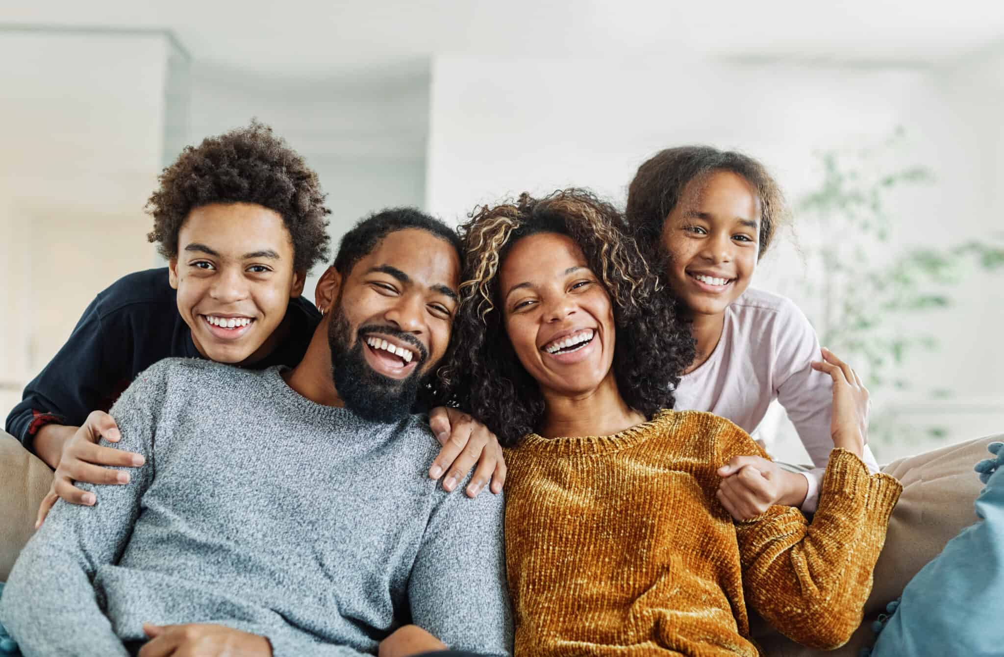 Black family on the couch smiling together.
