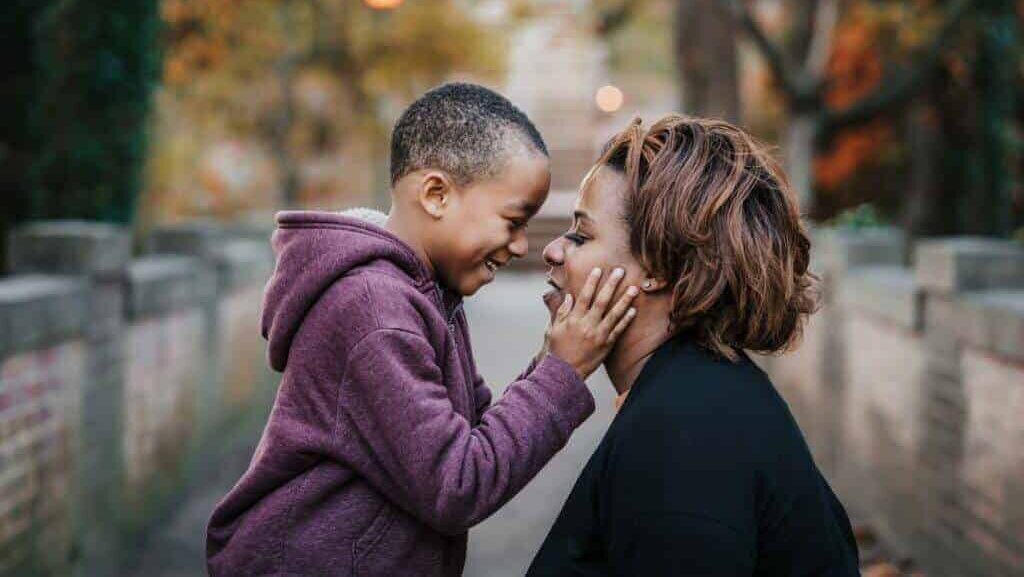 Black mom and son smiling at each other.