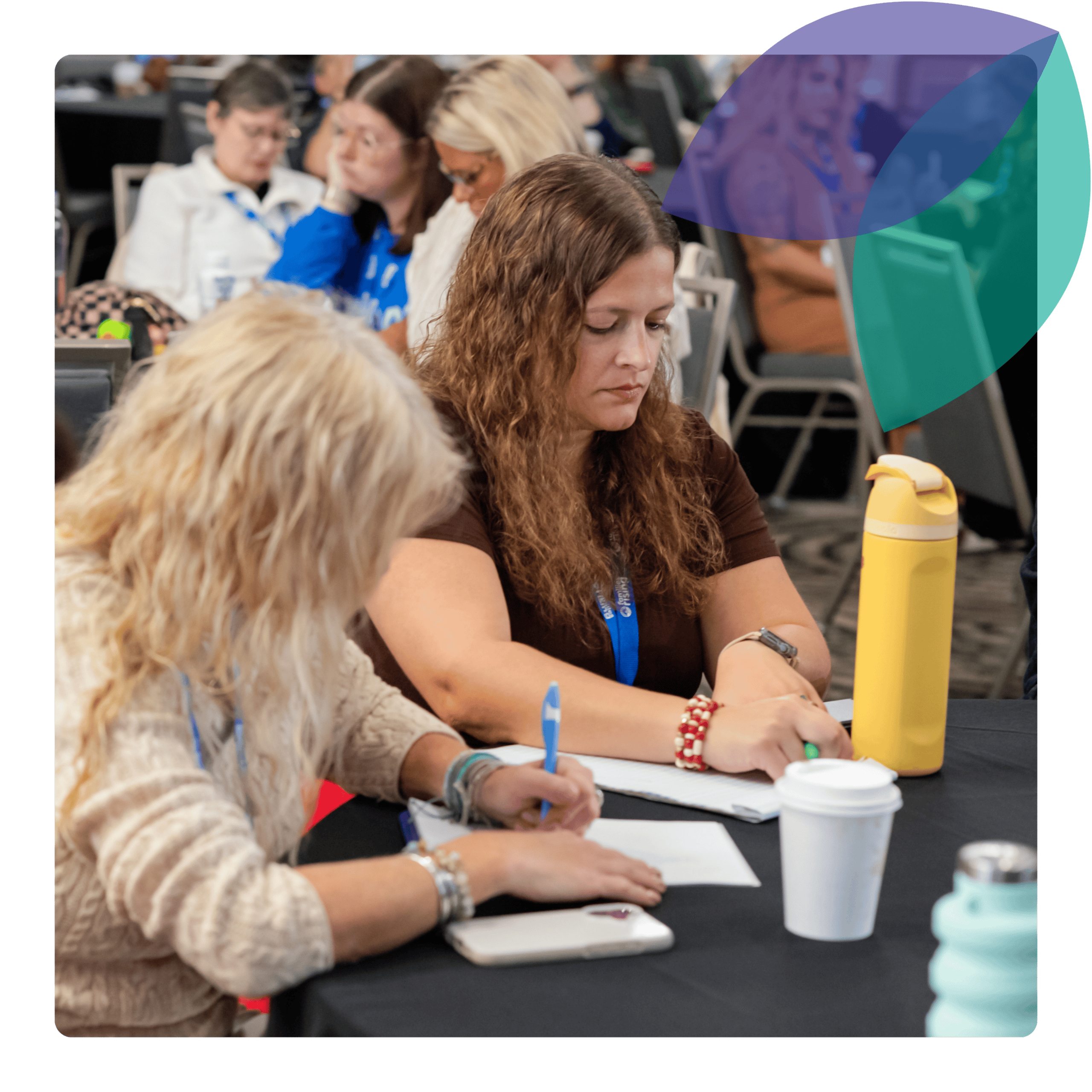 Training page body photo (1) Two child welfare professionals, possibly social workers, are sitting at a table with their heads down writing some notes